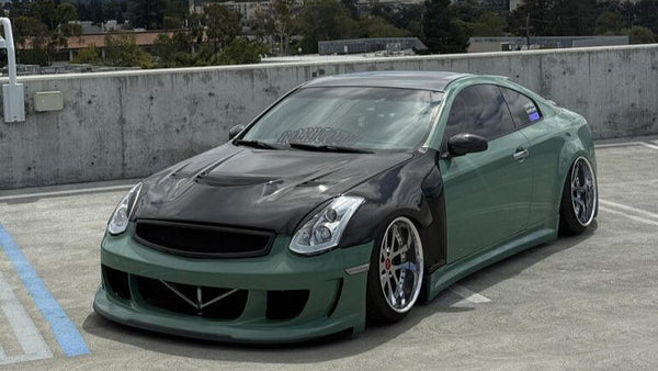 Green G35 Coupe car on a rooftop with a cityscape and mountains in the background